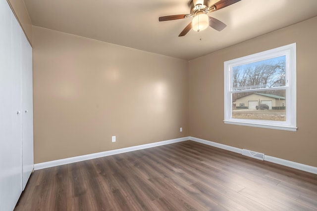 spare room featuring a ceiling fan, baseboards, visible vents, and dark wood-style flooring