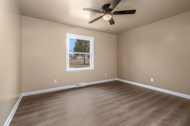 spare room featuring dark wood-style floors, visible vents, baseboards, and a ceiling fan