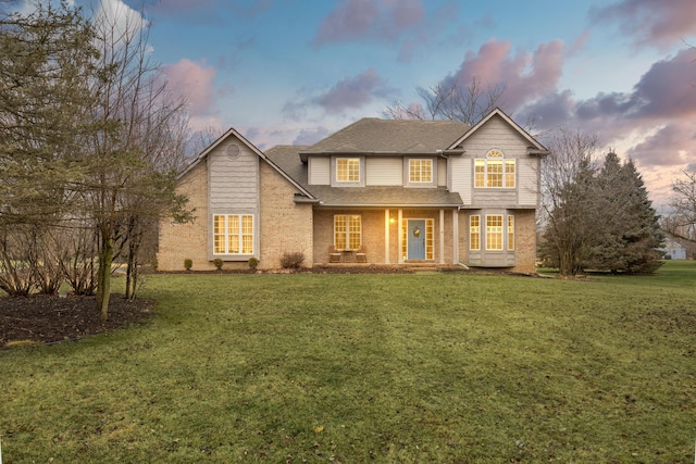 traditional-style house with roof with shingles, a front lawn, and brick siding