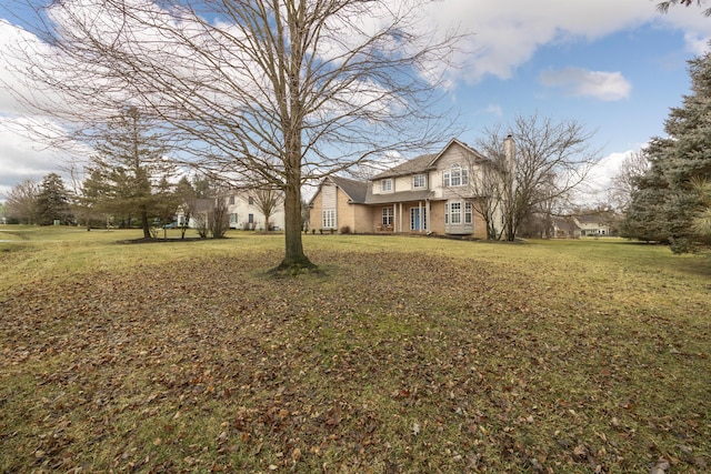 view of front of house with brick siding, a chimney, and a front lawn