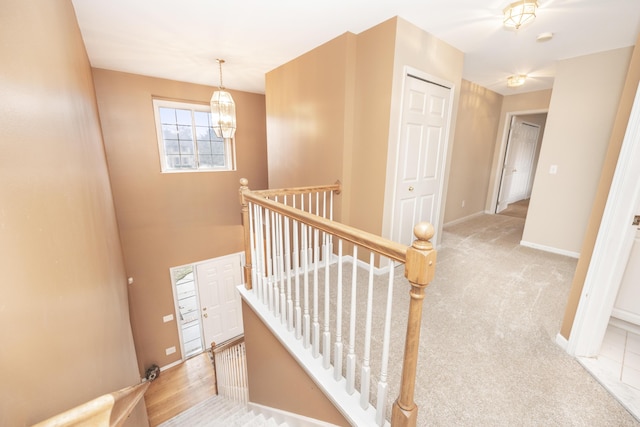 stairs with an inviting chandelier, carpet flooring, and baseboards