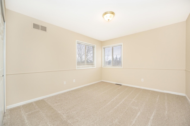 carpeted empty room featuring visible vents and baseboards