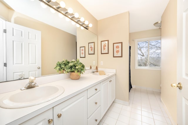 bathroom featuring double vanity, baseboards, a sink, and tile patterned floors