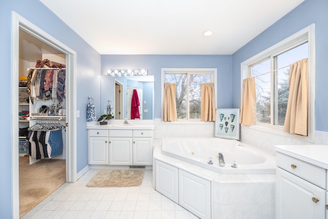 bathroom featuring visible vents, a tub with jets, tile patterned flooring, a spacious closet, and vanity