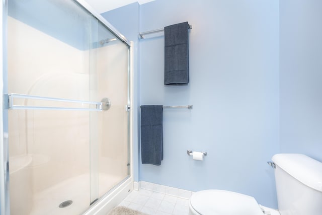 full bath with a stall shower, tile patterned flooring, baseboards, and toilet