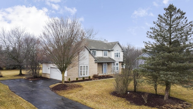 traditional home featuring an attached garage, driveway, a chimney, and a front yard