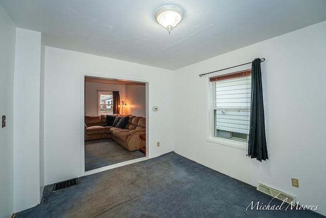 spare room with visible vents and dark colored carpet