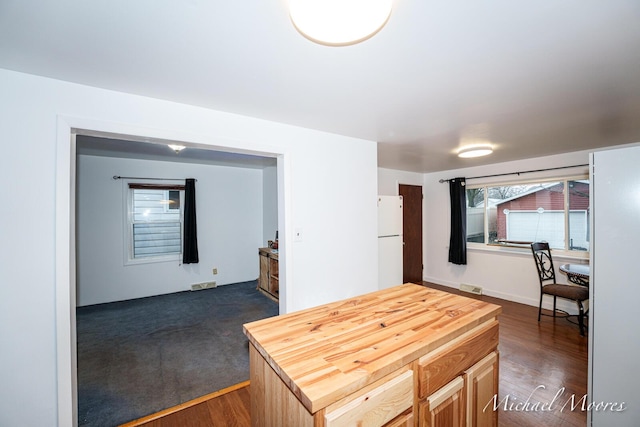 kitchen featuring wood counters, visible vents, dark wood-type flooring, and freestanding refrigerator