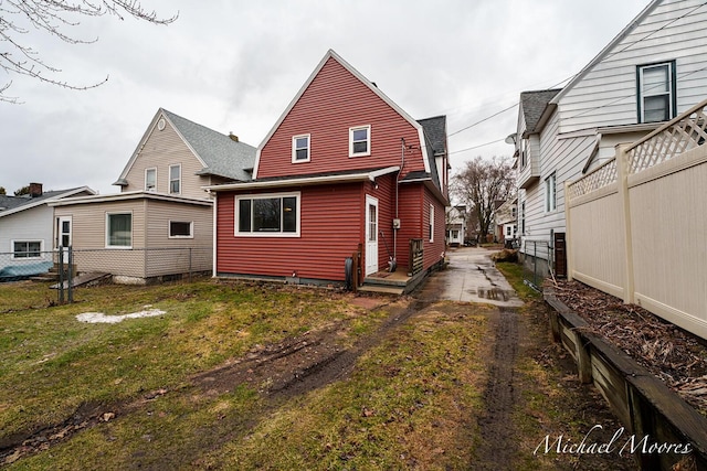 back of house with a yard, fence, and a gambrel roof