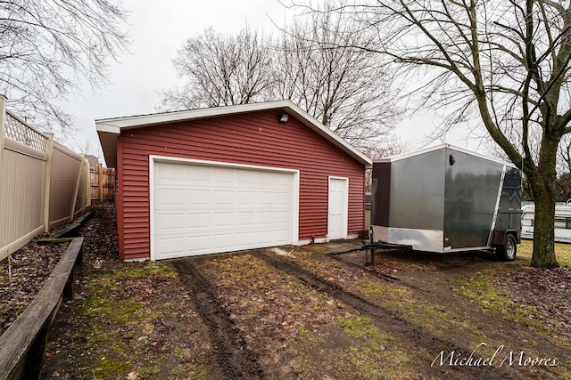 detached garage featuring driveway and fence