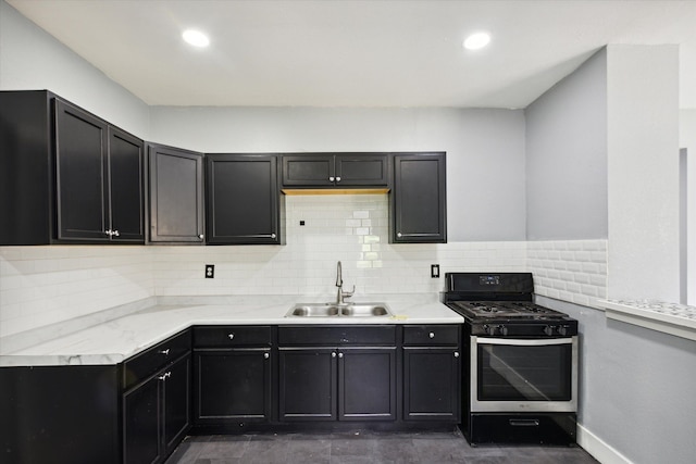 kitchen with tasteful backsplash, light countertops, a sink, and stainless steel gas range oven