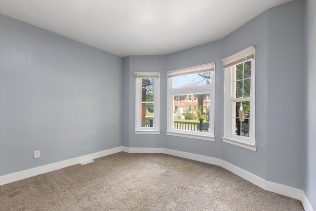 unfurnished room with carpet, visible vents, and baseboards