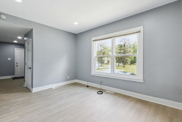 empty room featuring light wood-style floors, visible vents, and baseboards