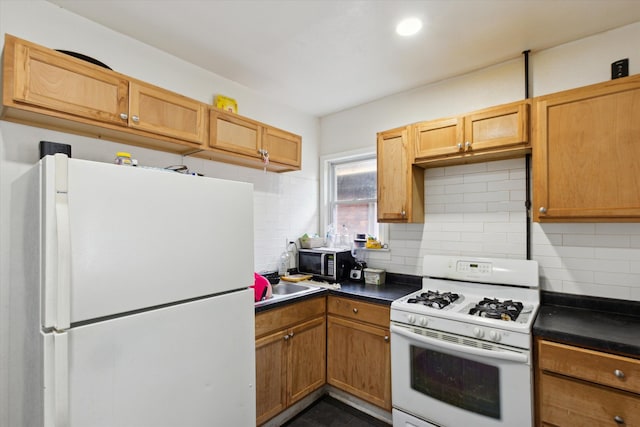 kitchen with dark countertops, white appliances, a sink, and backsplash