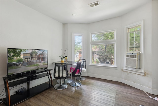 interior space with cooling unit, visible vents, baseboards, and wood finished floors