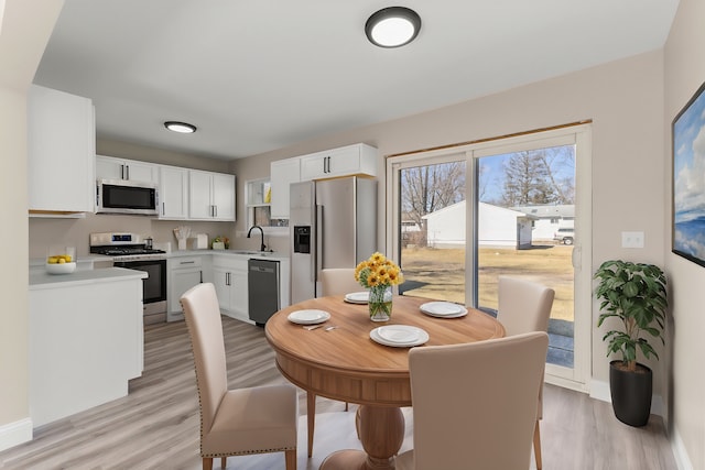 dining area featuring light wood finished floors and baseboards