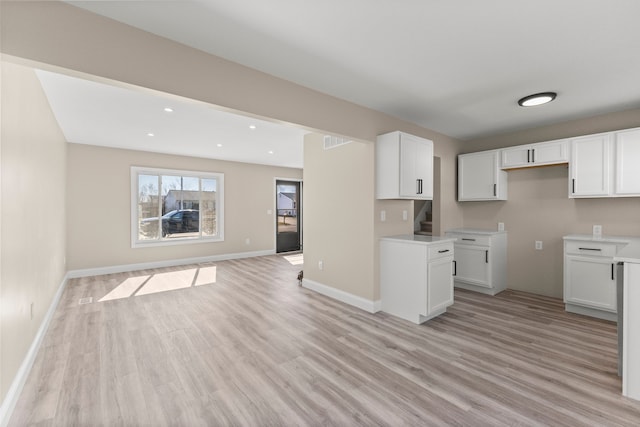 kitchen featuring baseboards, light wood-style flooring, recessed lighting, white cabinetry, and open floor plan