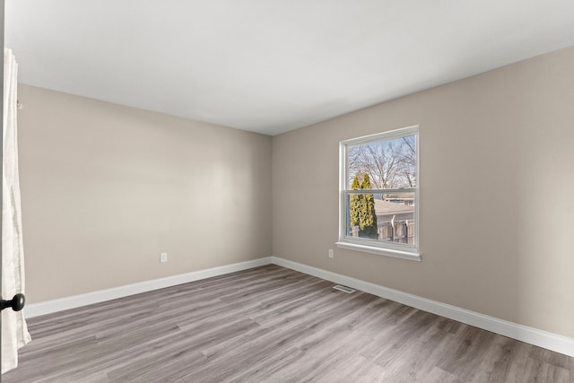 empty room with visible vents, baseboards, and light wood finished floors