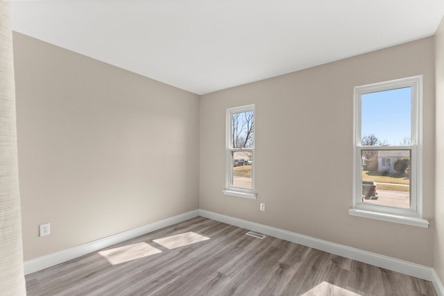 empty room with visible vents, baseboards, and light wood finished floors