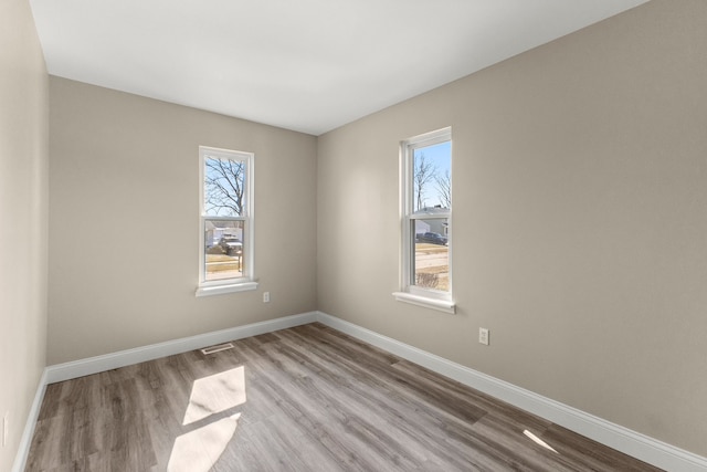 unfurnished room featuring visible vents, baseboards, and wood finished floors