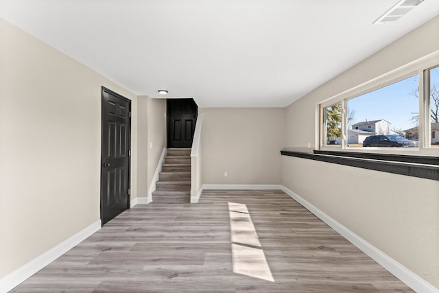 unfurnished room with stairway, baseboards, visible vents, and light wood-style flooring