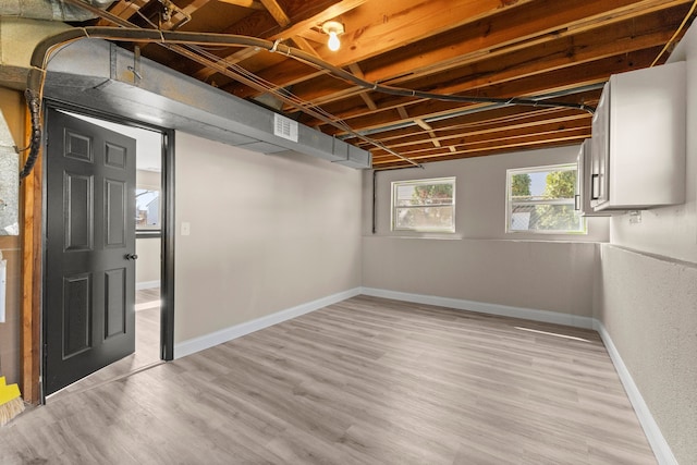 basement featuring visible vents, light wood-style flooring, and baseboards