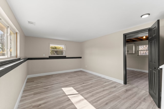 spare room with baseboards and light wood-style floors