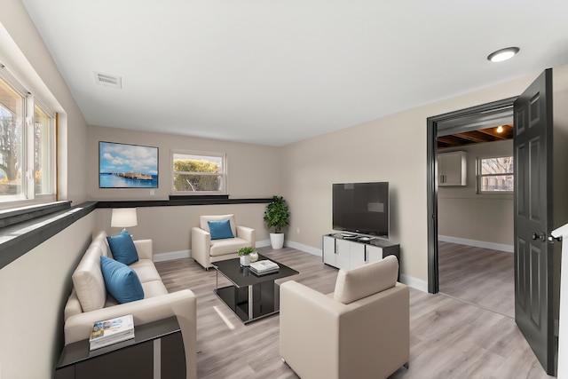 living room featuring visible vents, baseboards, and light wood finished floors