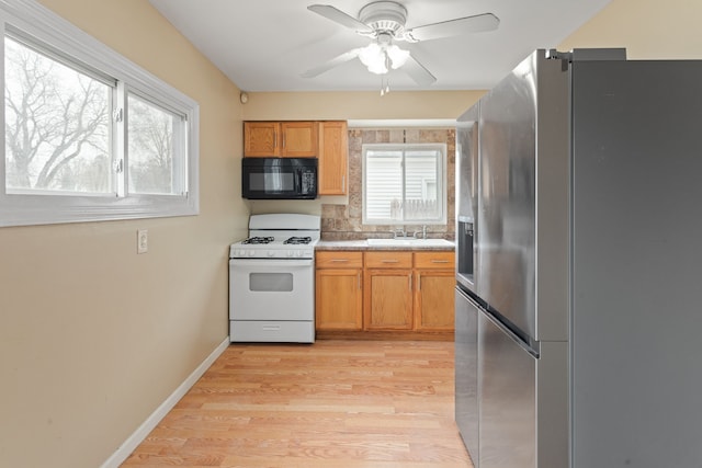 kitchen featuring black microwave, light wood-type flooring, gas range gas stove, and stainless steel refrigerator with ice dispenser