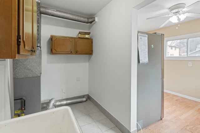 interior space featuring cabinet space, a ceiling fan, baseboards, and a sink