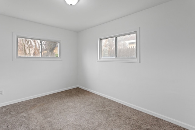 carpeted spare room featuring a wealth of natural light and baseboards