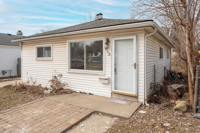 exterior space with roof with shingles and a patio area