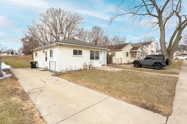 bungalow-style house with a front yard, fence, and a chimney