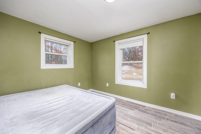 9915 85th Ave, Mecosta, MI 49332 - bedroom with baseboards, wood tiled floor, and multiple windows