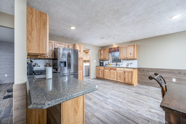 9915 85th Ave, Mecosta, MI 49332 - kitchen with tasteful backsplash, light wood-type flooring, a sink, washer / dryer, and stainless steel fridge