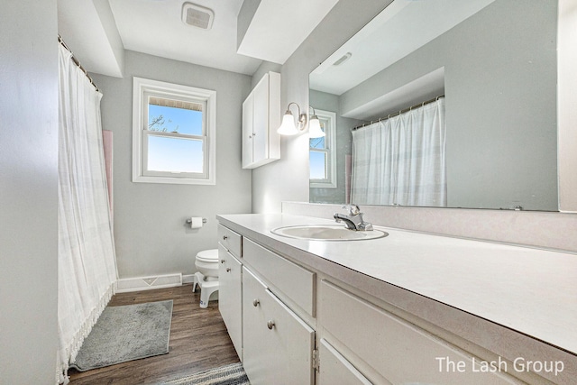 bathroom featuring toilet, wood finished floors, visible vents, vanity, and baseboards