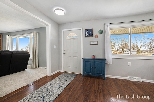 foyer entrance featuring dark wood-style floors, visible vents, and baseboards