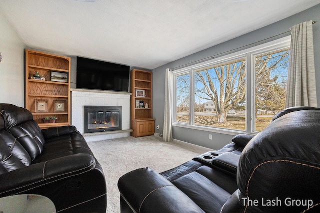 living area featuring a glass covered fireplace, baseboards, and carpet