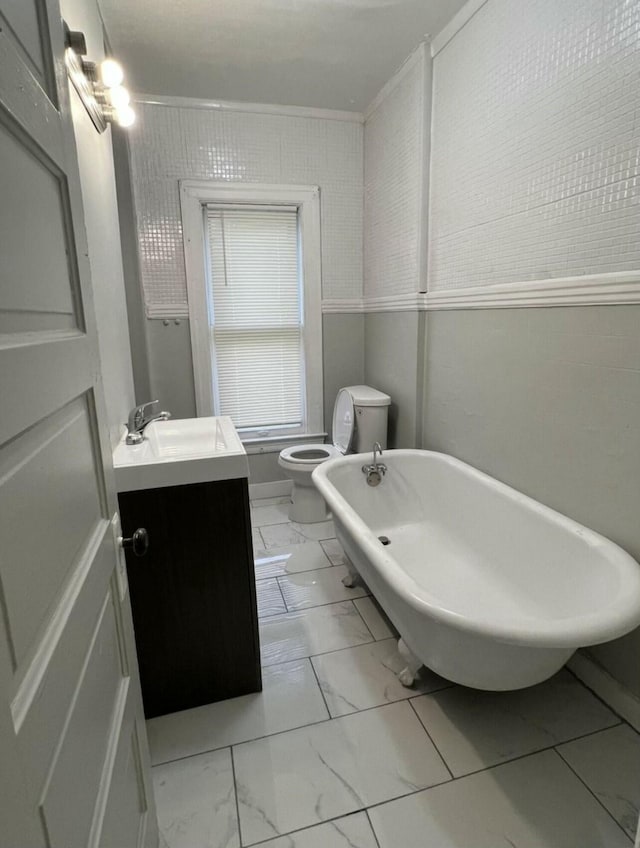 bathroom with toilet, marble finish floor, vanity, and a soaking tub