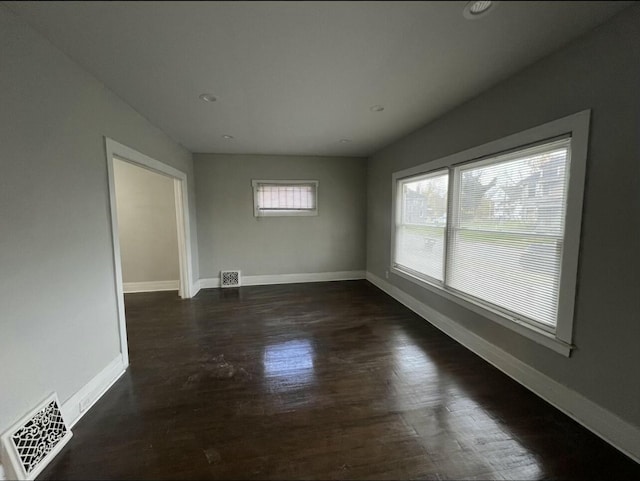 unfurnished room with baseboards, visible vents, and dark wood-type flooring