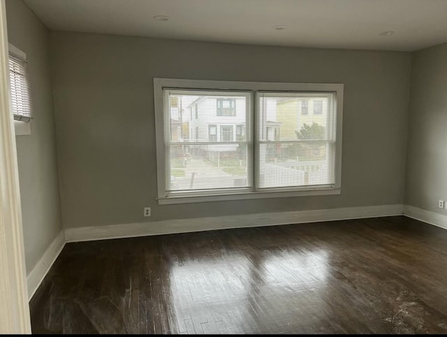 unfurnished room with dark wood-style flooring and baseboards