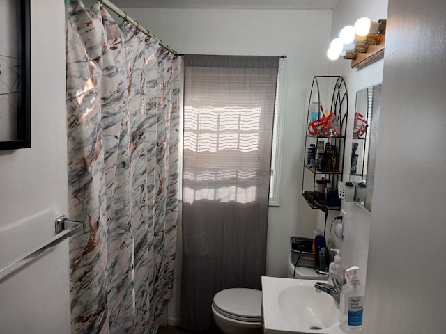 bathroom with toilet, a shower with shower curtain, and a sink