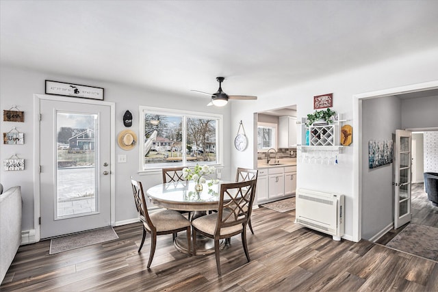 dining space featuring heating unit, a ceiling fan, baseboards, dark wood finished floors, and a baseboard heating unit