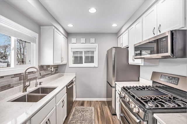 kitchen with dark wood-style floors, white cabinets, stainless steel appliances, and a sink