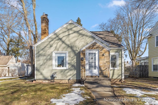 bungalow featuring a front lawn, a chimney, and fence