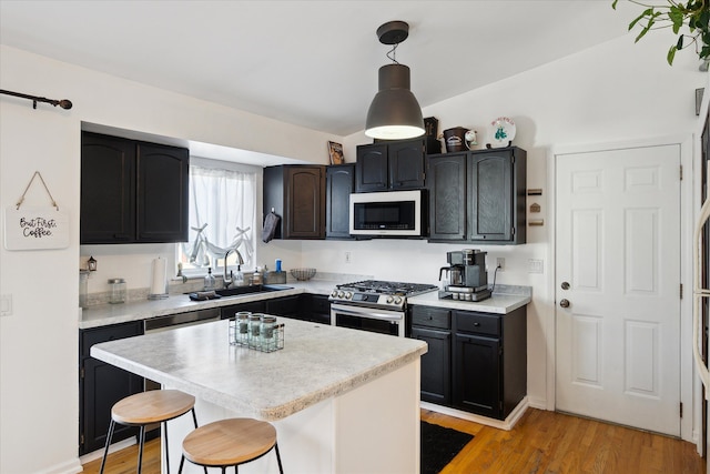 kitchen featuring a sink, light countertops, light wood finished floors, gas stove, and a kitchen bar