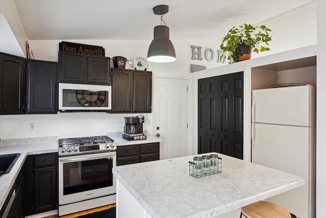 kitchen featuring stainless steel gas stove, light countertops, freestanding refrigerator, and decorative light fixtures