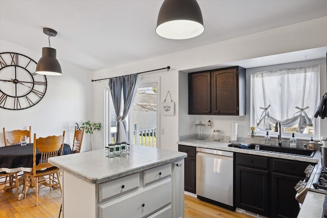 kitchen featuring pendant lighting, light countertops, a kitchen island, light wood-type flooring, and dishwasher