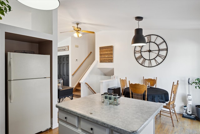 kitchen featuring a ceiling fan, a kitchen island, freestanding refrigerator, light countertops, and light wood-style floors