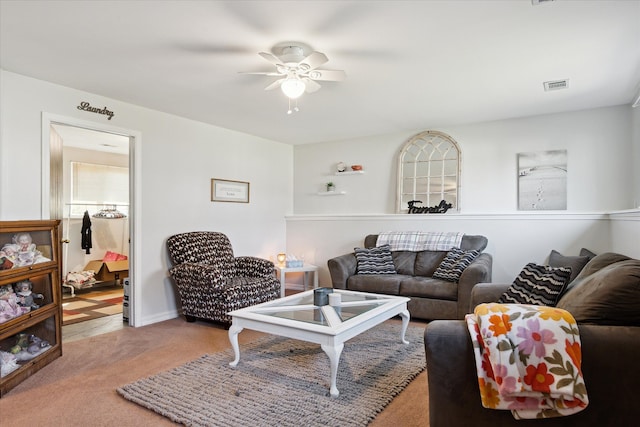 living room with light carpet, visible vents, and a ceiling fan